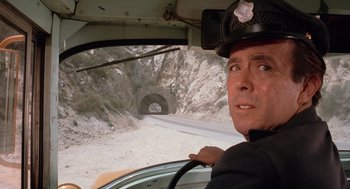 Movie still from “Duel” (1971), directed by Steven Spielberg – A man in a police uniform sitting in the driver's seat of a car; Close Up shot, Over the shoulder angle