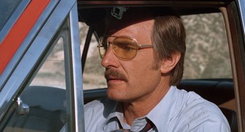 Movie still from “Duel” (1971), directed by Steven Spielberg – A person in a car wearing glasses; Close Up shot, Low angle