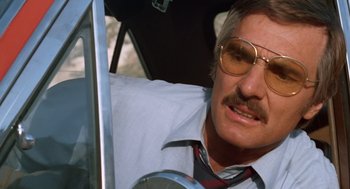 Movie still from “Duel” (1971), directed by Steven Spielberg – A person in a car wearing glasses; Close Up shot, Low angle