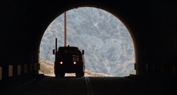 Movie still from “Duel” (1971), directed by Steven Spielberg – A truck driving through a tunnel on the side of a mountain; Extreme Wide shot, Low angle