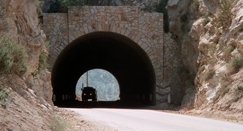 Movie still from “Duel” (1971), directed by Steven Spielberg – A truck is driving through a tunnel on the side of the road; Extreme Wide shot, Low angle