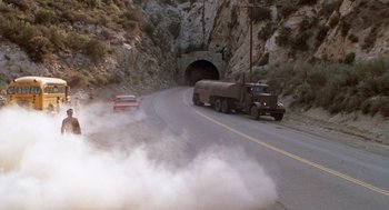 Movie still from “Duel” (1971), directed by Steven Spielberg – A truck driving down a road near a tunnel with smoke coming out of it; Extreme Wide shot, High angle