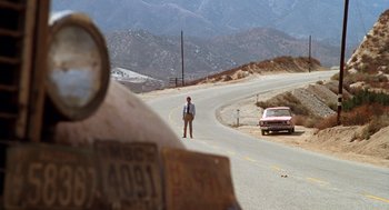 Movie still from “Duel” (1971), directed by Steven Spielberg – A man standing on the side of a road near a car; Extreme Wide shot, Over the shoulder angle