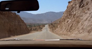 Movie still from “Duel” (1971), directed by Steven Spielberg – A view from a car looking out the windshield at a mountain; Extreme Wide shot, High angle