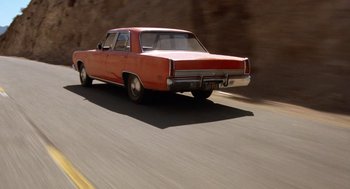 Movie still from “Duel” (1971), directed by Steven Spielberg – An orange car is driving down the street; Wide shot, Low angle