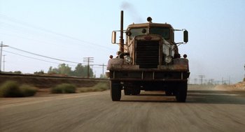 Movie still from “Duel” (1971), directed by Steven Spielberg – An old truck is driving down the street; Wide shot, Low angle