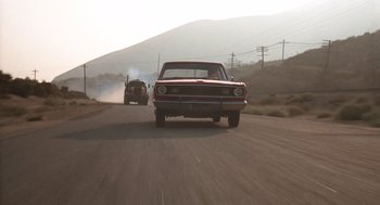 Movie still from “Duel” (1971), directed by Steven Spielberg – A couple of cars driving down a street; Wide shot, Low angle