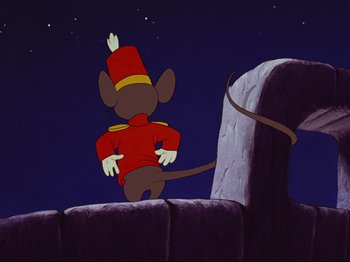 Movie still from “Dumbo” (1941), directed by Ben Sharpsteen – A mouse wearing a red outfit standing next to a stone wall; Medium shot, Low angle
