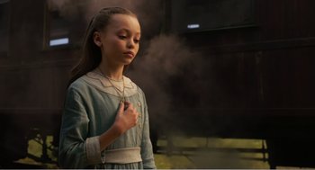 Movie still from “Dumbo” (2019), directed by Tim Burton – A young girl is standing in front of a smoke filled building; Medium shot, Low angle
