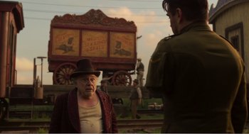 Movie still from “Dumbo” (2019), directed by Tim Burton – An older man and a young man standing next to a train; Medium shot, Over the shoulder angle