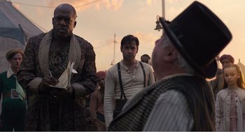 Movie still from “Dumbo” (2019), directed by Tim Burton – A group of men standing next to each other on a field; Medium shot, Over the shoulder angle