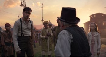 Movie still from “Dumbo” (2019), directed by Tim Burton – A group of people standing around a field; Medium shot, Over the shoulder angle