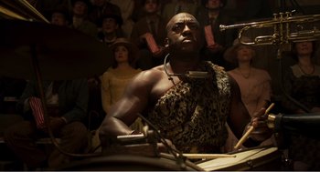 Movie still from “Dumbo” (2019), directed by Tim Burton – A man is playing the drums in front of a crowd; Medium shot, Low angle