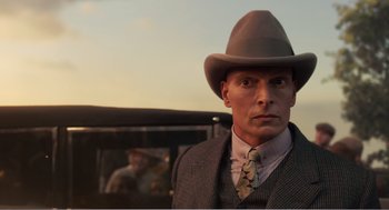 Movie still from “Dumbo” (2019), directed by Tim Burton – A man wearing a hat and a suit and tie; Close Up shot, Over the shoulder angle