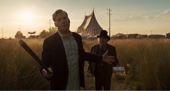 Movie still from “Dumbo” (2019), directed by Tim Burton – Two men in suits and hats are standing in a field; Medium shot, Low angle