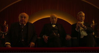 Movie still from “Dumbo” (2019), directed by Tim Burton – A group of men sitting in a row on a theater seat; Medium shot, Low angle