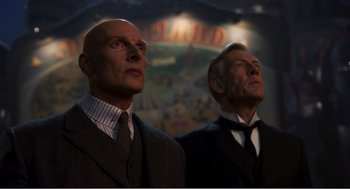 Movie still from “Dumbo” (2019), directed by Tim Burton – A couple of men standing next to each other; Medium shot, Low angle