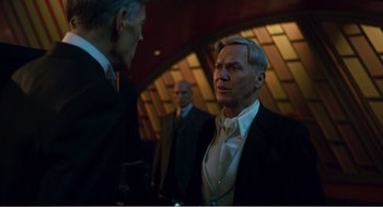 Movie still from “Dumbo” (2019), directed by Tim Burton – A man in a suit talking to another man in a suit; Medium shot, Over the shoulder angle