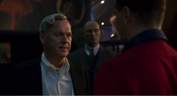 Movie still from “Dumbo” (2019), directed by Tim Burton – A man in a suit is talking to two other men; Close Up shot, Over the shoulder angle