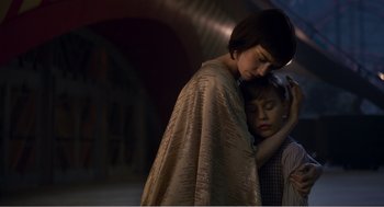 Movie still from “Dumbo” (2019), directed by Tim Burton – A woman and a boy are hugging in a tunnel; Medium shot, Low angle