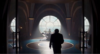 Movie still from “Dumbo” (2019), directed by Tim Burton – A man is standing in front of a large window; Wide shot, Over the shoulder angle