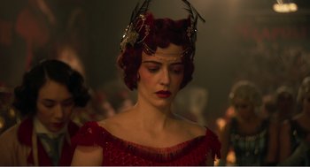 Movie still from “Dumbo” (2019), directed by Tim Burton – A woman in a red dress with a bird head piece; Close Up shot, Over the shoulder angle