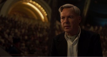 Movie still from “Dumbo” (2019), directed by Tim Burton – An older man in a suit and white shirt is in front of an audience; Close Up shot, Over the shoulder angle