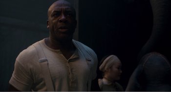 Movie still from “Dumbo” (2019), directed by Tim Burton – A man standing next to a woman in front of a wall; Medium shot, Over the shoulder angle