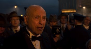 Movie still from “Dumbo” (2019), directed by Tim Burton – An older man in a tuxedo and a bow tie; Medium shot, Over the shoulder angle
