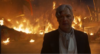 Movie still from “Dumbo” (2019), directed by Tim Burton – A man standing in front of a burning fire; Close Up shot, Over the shoulder angle