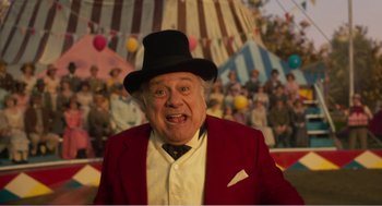 Movie still from “Dumbo” (2019), directed by Tim Burton – An older man in a red jacket and a black hat; Medium shot, Low angle