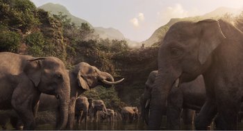 Movie still from “Dumbo” (2019), directed by Tim Burton – A herd of elephants walking across a lush green forest; Extreme Wide shot, Low angle
