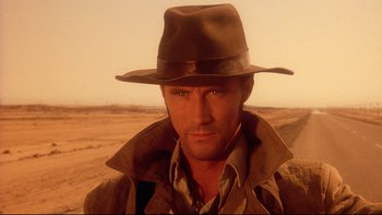 Movie still from “Dust Devil” (1992), directed by Richard Stanley – A person wearing a hat; Close Up shot, Over the shoulder angle