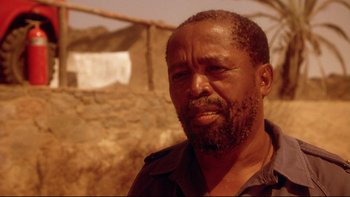 Movie still from “Dust Devil” (1992), directed by Richard Stanley – A person with a beard; Close Up shot, Low angle