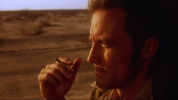 Movie still from “Dust Devil” (1992), directed by Richard Stanley – A person holding a cell phone to his ear; Close Up shot, Low angle