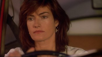 Movie still from “Dust Devil” (1992), directed by Richard Stanley – A person sitting in a car holding a steering wheel; Close Up shot, Over the shoulder angle