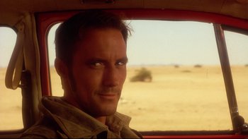 Movie still from “Dust Devil” (1992), directed by Richard Stanley – A person in a car; Close Up shot, Over the shoulder angle