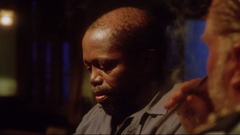 Movie still from “Dust Devil” (1992), directed by Richard Stanley – A person with a beard; Close Up shot, Low angle