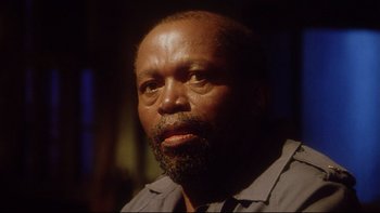 Movie still from “Dust Devil” (1992), directed by Richard Stanley – A person with a beard looking into the distance; Close Up shot, Low angle