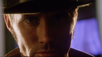 Movie still from “Dust Devil” (1992), directed by Richard Stanley – A man wearing a hat and looking into the camera; Extreme Close Up shot, Low angle