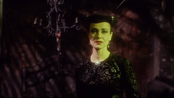 Movie still from “Dust Devil” (1992), directed by Richard Stanley – A woman in a black dress and a green hat; Close Up shot, Low angle