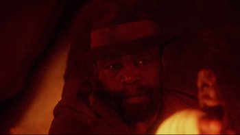 Movie still from “Dust Devil” (1992), directed by Richard Stanley – A person wearing a hat; Close Up shot, High angle