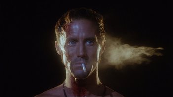 Movie still from “Dust Devil” (1992), directed by Richard Stanley – A person smoking a cigarette with smoke coming out; Close Up shot, Low angle