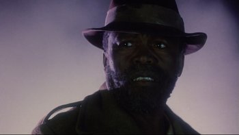 Movie still from “Dust Devil” (1992), directed by Richard Stanley – A person wearing a hat; Close Up shot, Low angle