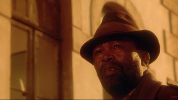 Movie still from “Dust Devil” (1992), directed by Richard Stanley – A person wearing a hat; Close Up shot, Low angle