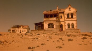 Movie still from “Dust Devil” (1992), directed by Richard Stanley – An old house in the middle of a desert; Extreme Wide shot, Low angle