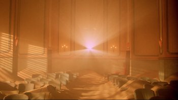 Movie still from “Dust Devil” (1992), directed by Richard Stanley – The sun is shining through the window of a building; Extreme Wide shot, High angle