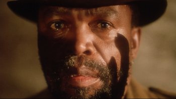Movie still from “Dust Devil” (1992), directed by Richard Stanley – A person wearing a hat; Extreme Close Up shot, Low angle