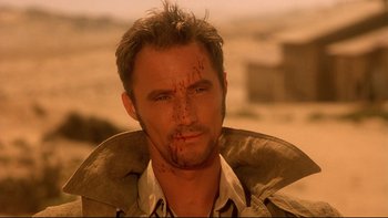 Movie still from “Dust Devil” (1992), directed by Richard Stanley – A person with a scar on his face; Close Up shot, Over the shoulder angle