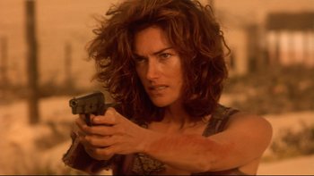 Movie still from “Dust Devil” (1992), directed by Richard Stanley – A woman holding a gun in her hand; Close Up shot, Low angle